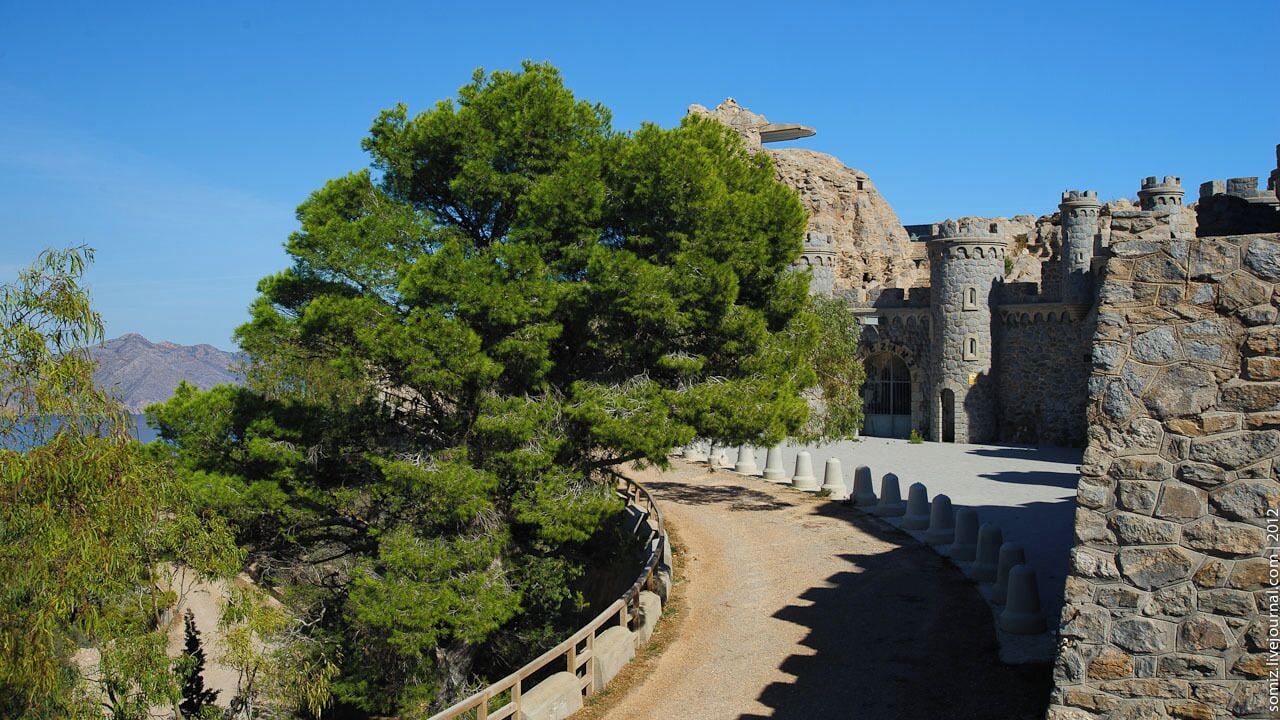 A stone castle with a large tree in front.