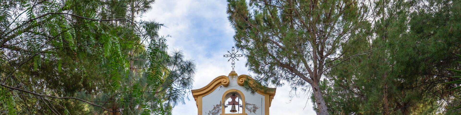 A church with a bell tower, surrounded by lush greenery.