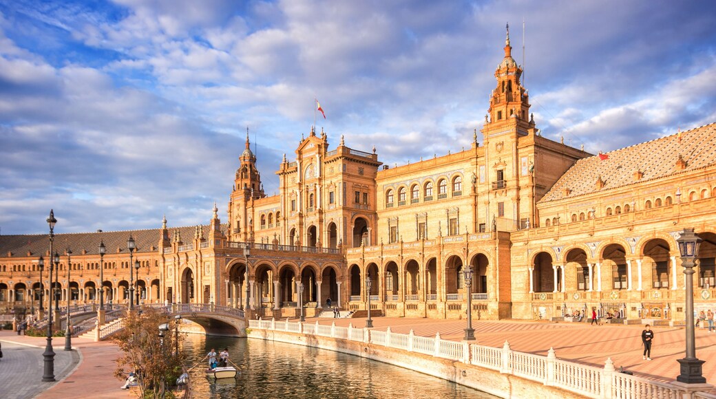 A grand historic building with multiple arches and a river in the foreground.