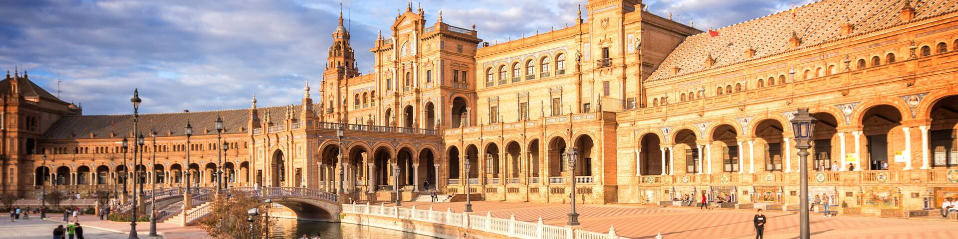 A grand historic building with multiple arches and a river in the foreground.