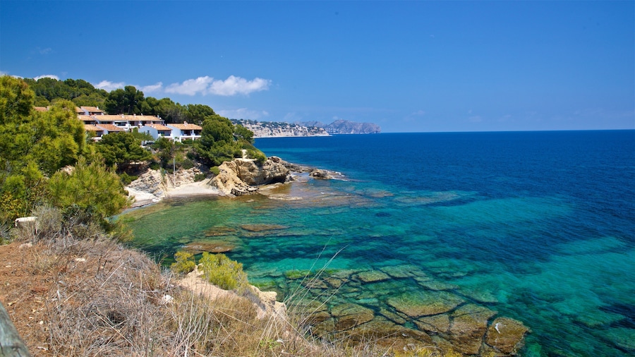 A coastal landscape with clear turquoise waters, rocky shorelines, and a cluster of houses on a hillside.