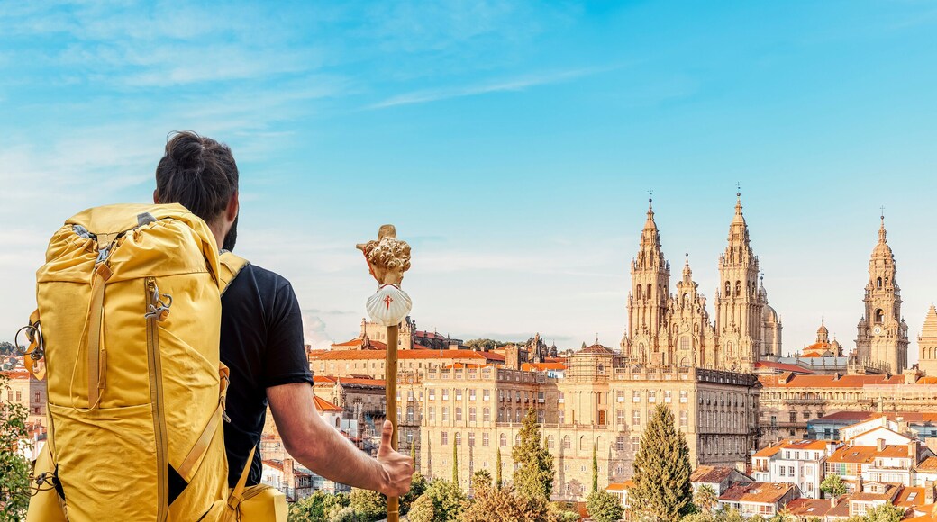Pilgrim on the Camino de Santiago (Saint James way) looking at the cathedral and the old town panoramic view of Santiago de Compostela, Galicia, Spain