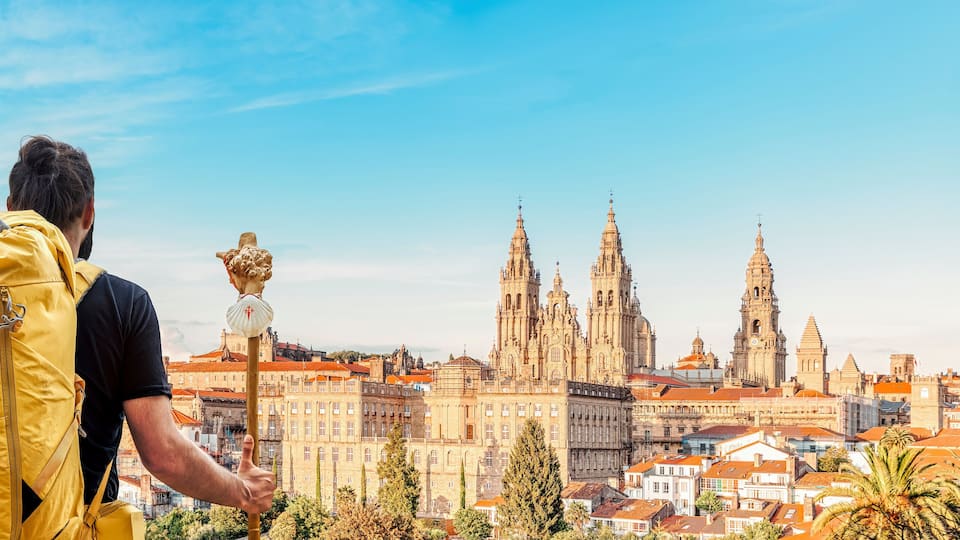 Pilgrim on the Camino de Santiago (Saint James way) looking at the cathedral and the old town panoramic view of Santiago de Compostela, Galicia, Spain