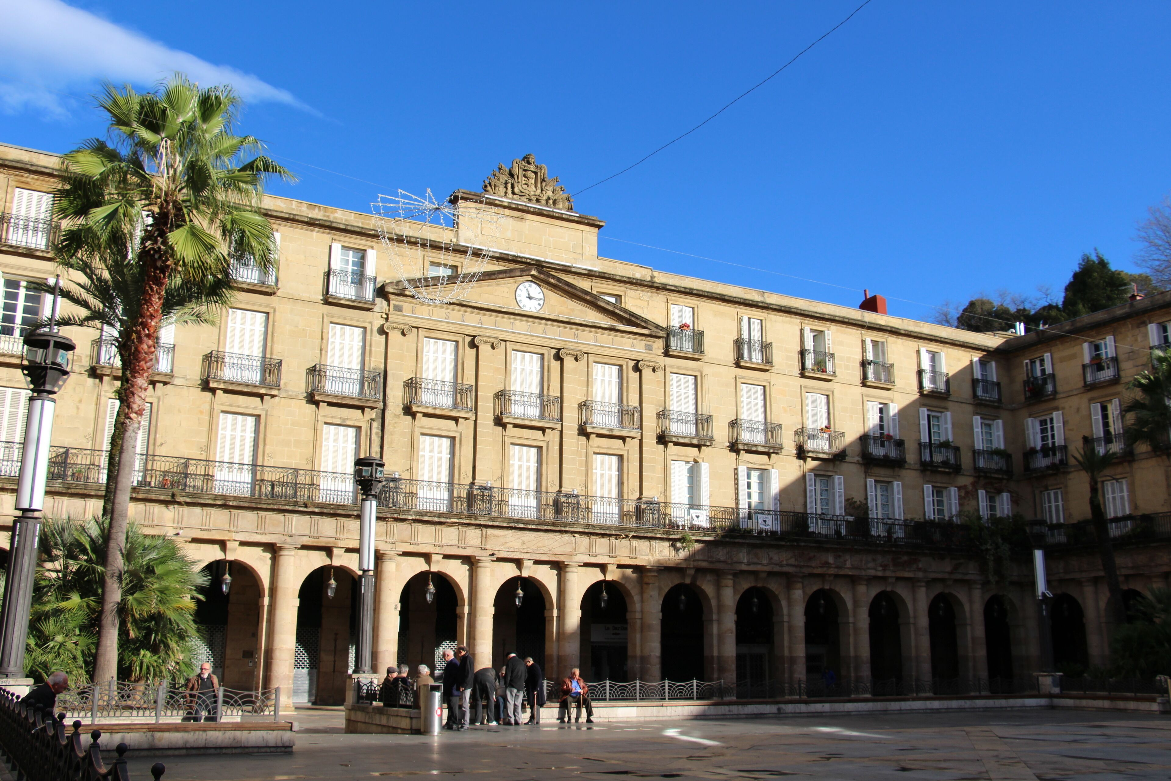 Un edificio histórico con múltiples balcones y arcos, rodeado de palmeras.