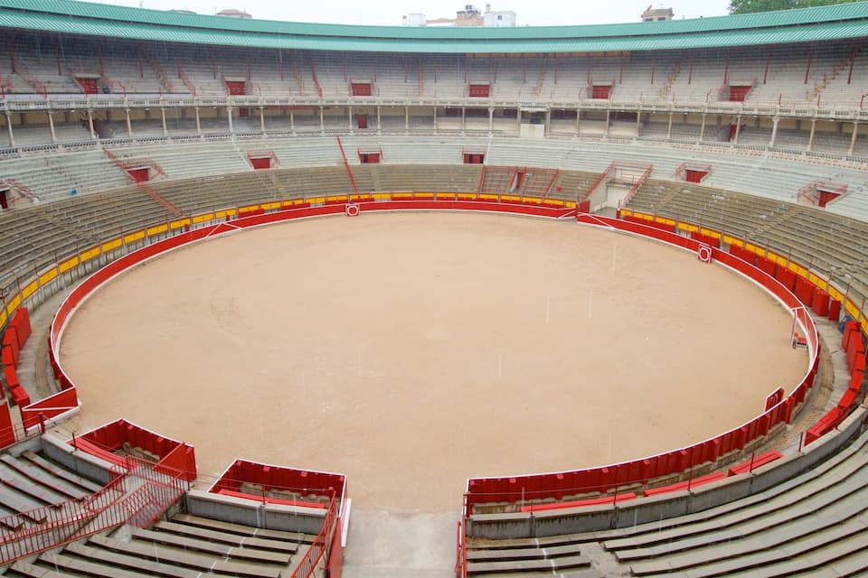 Un estadio grande y vacío con asientos escalonados y un foso de arena en el centro.