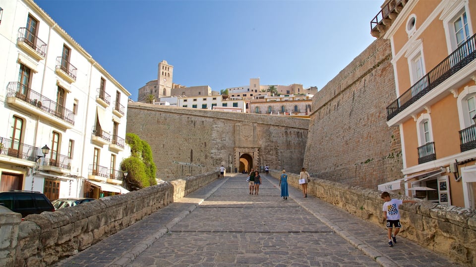 A stone staircase leading up to a historic gate, flanked by old buildings and a clear blue sky.