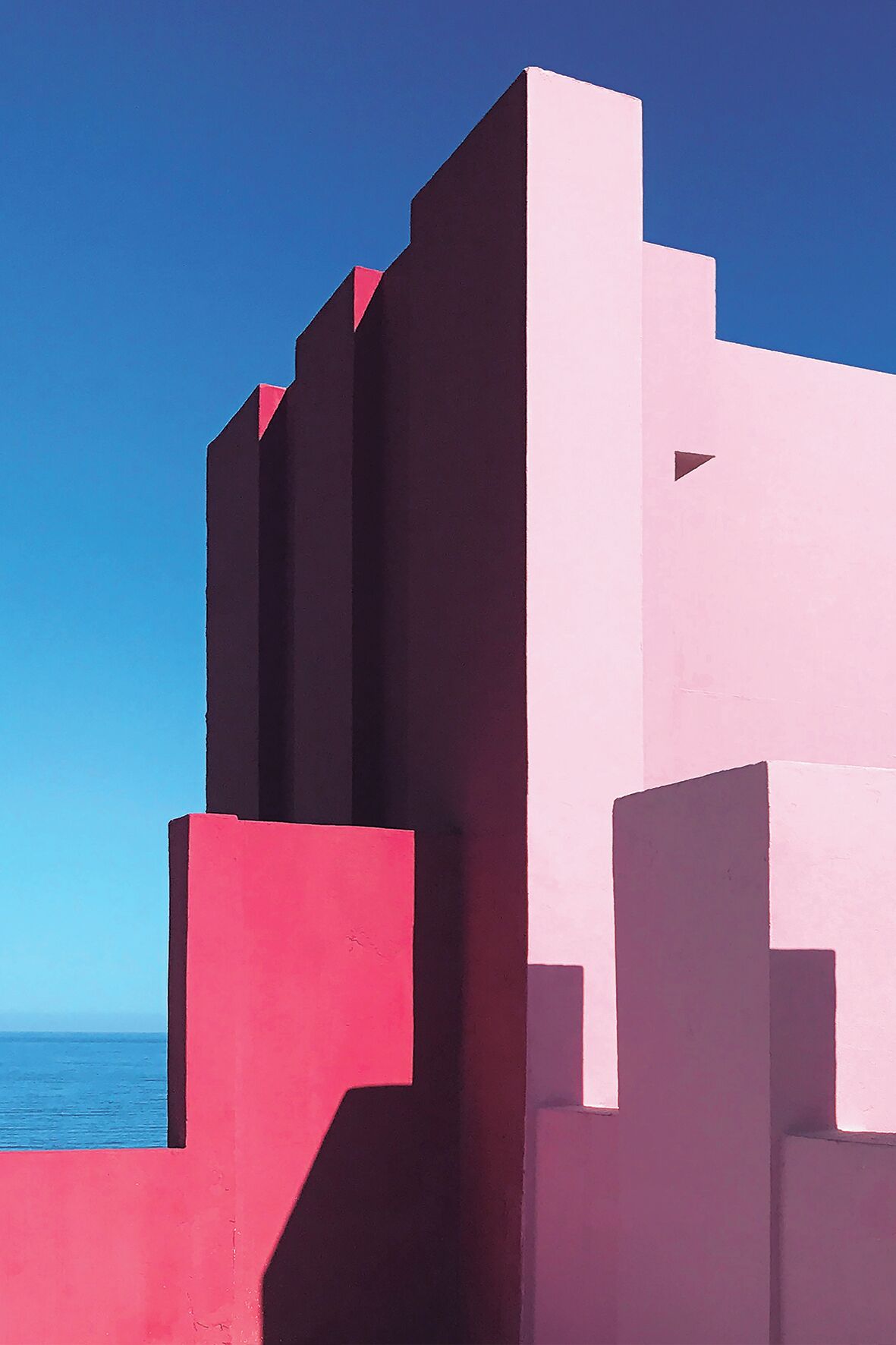A modern architectural structure with geometric shapes and a clear blue sky in the background.