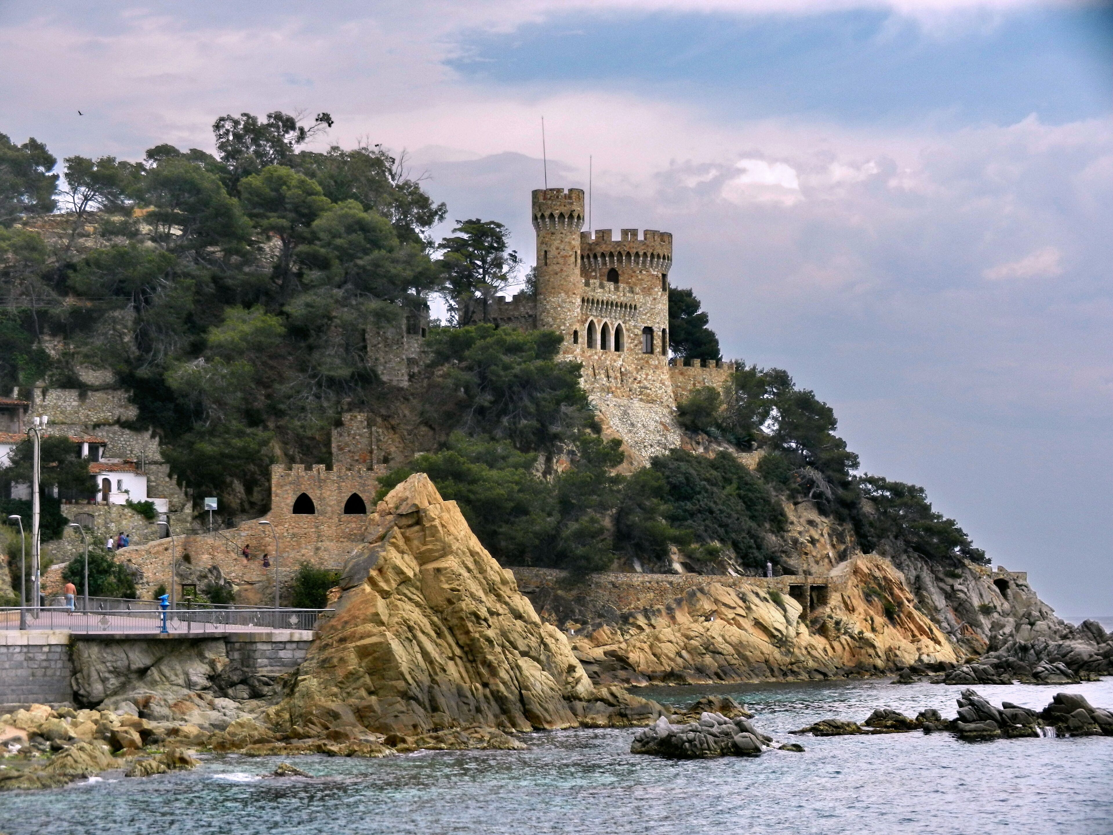 Un château côtier, perché sur une falaise rocheuse, auquel on accède par un pont.