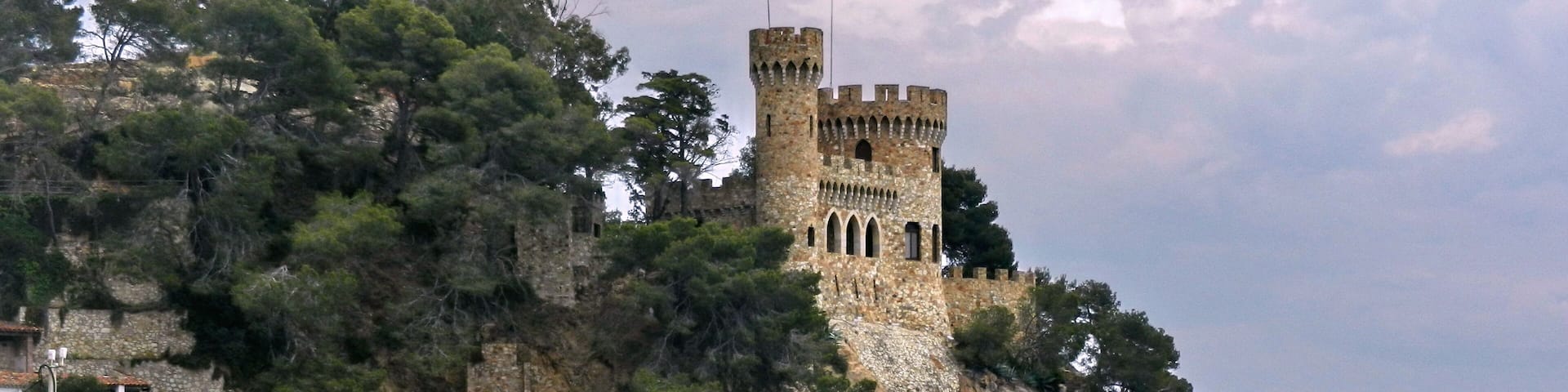 A coastal castle on a rocky cliff with a bridge leading to it.