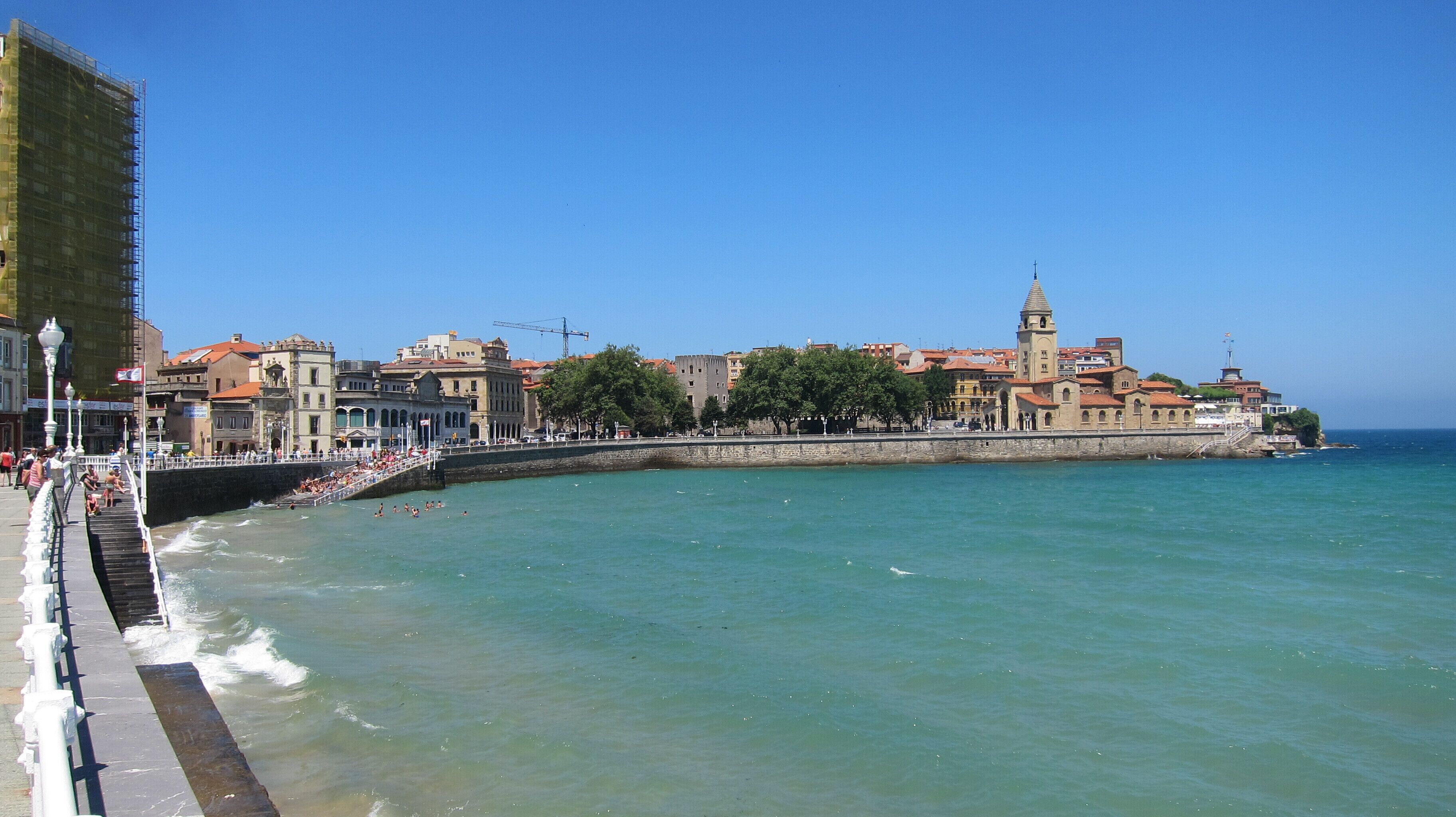 Eine Küstenstadt mit einem markanten Turm, einer Uferpromenade und historischen Gebäuden am Wasser.