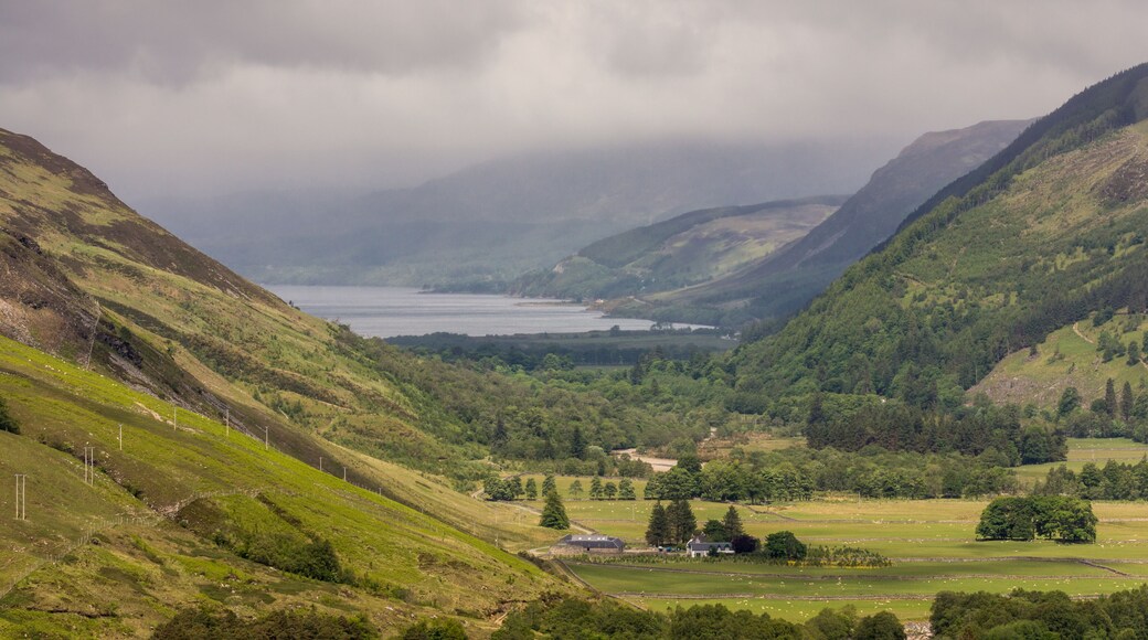 Braemore, Scotland - June 8, 2012: West of Corrieshalloch Gorge along A832 from height look upon Loch Broom under cloudy cloudscape. Green forested mountains. Meadows on slopes and valley.