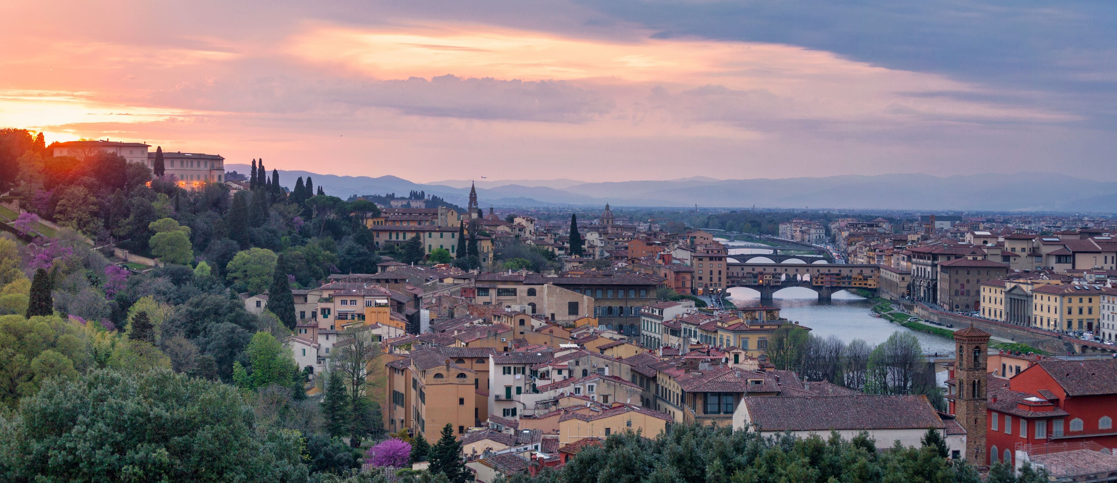 Panoramic view of Florence at sunset with in the background, the Basilica di Santo Spirito and its spire, the Church of San Frediano in Cestello and Ponte Vecchio.