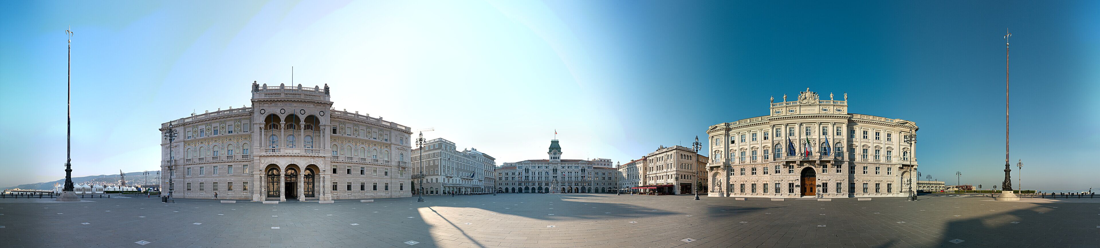 Un'ampia piazza aperta con edifici storici, tra cui un imponente edificio circolare con cupola e un altro con una torre centrale.