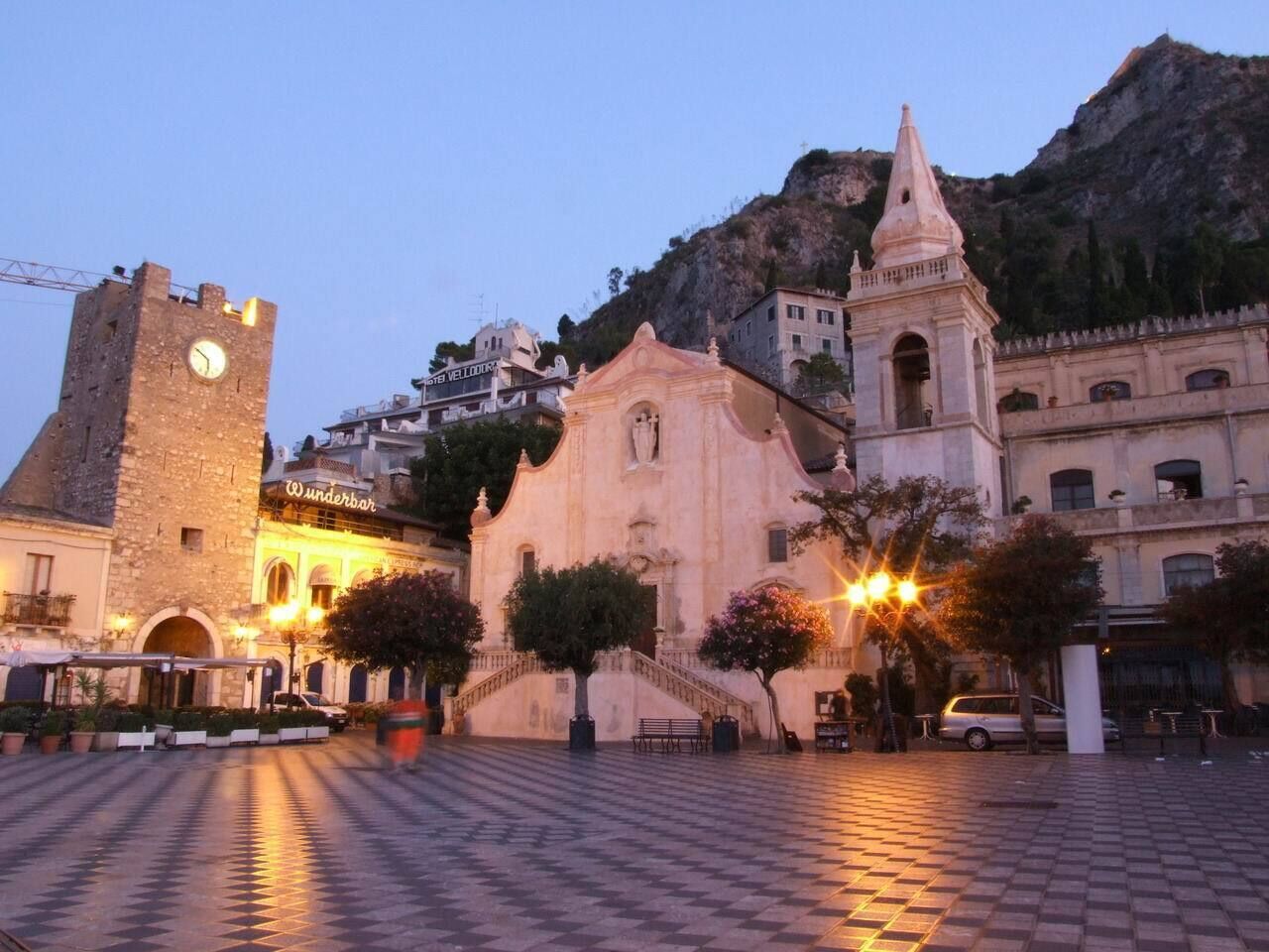 A historic square with a clock tower, a church, and a bar named 'Wunderbar'.