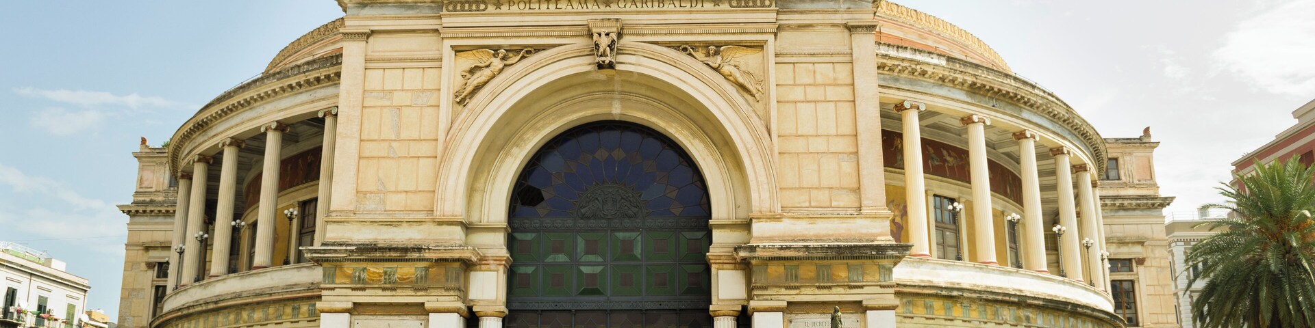 Um edifício imponente de estilo clássico, com um grande arco central e estátuas no topo.
