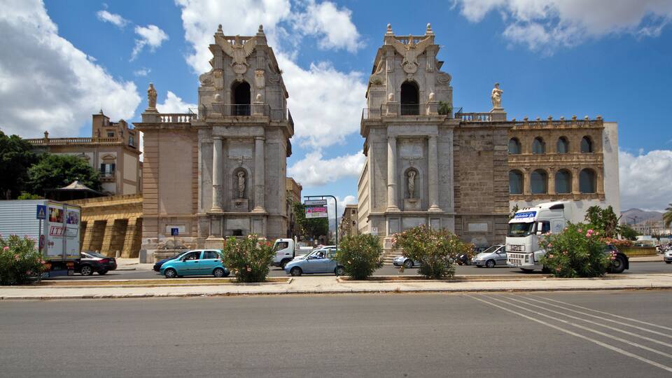 A historic building with two prominent towers and a large truck parked in front.