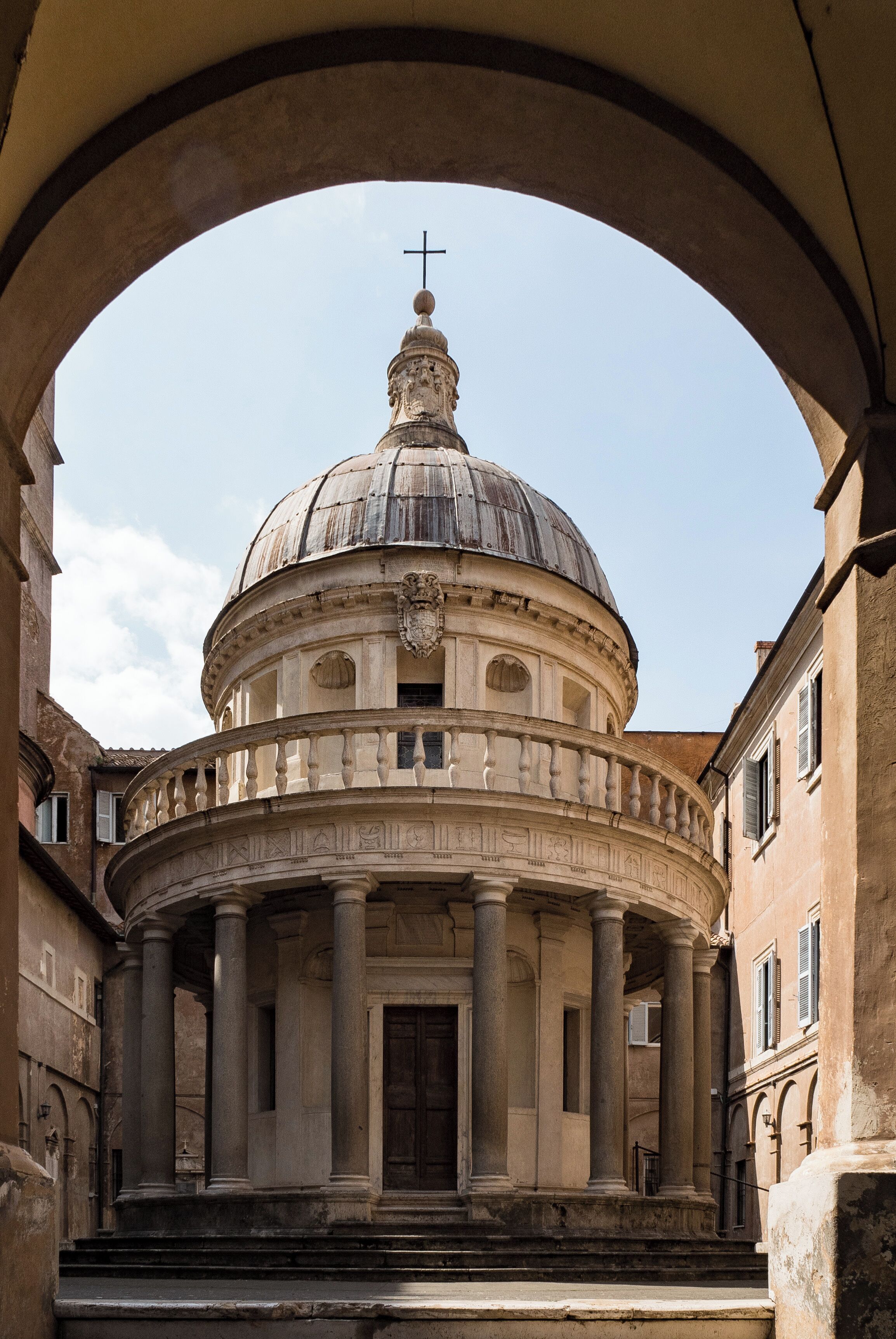 Un edificio histórico con una cúpula y columnas, enmarcado por un arco.