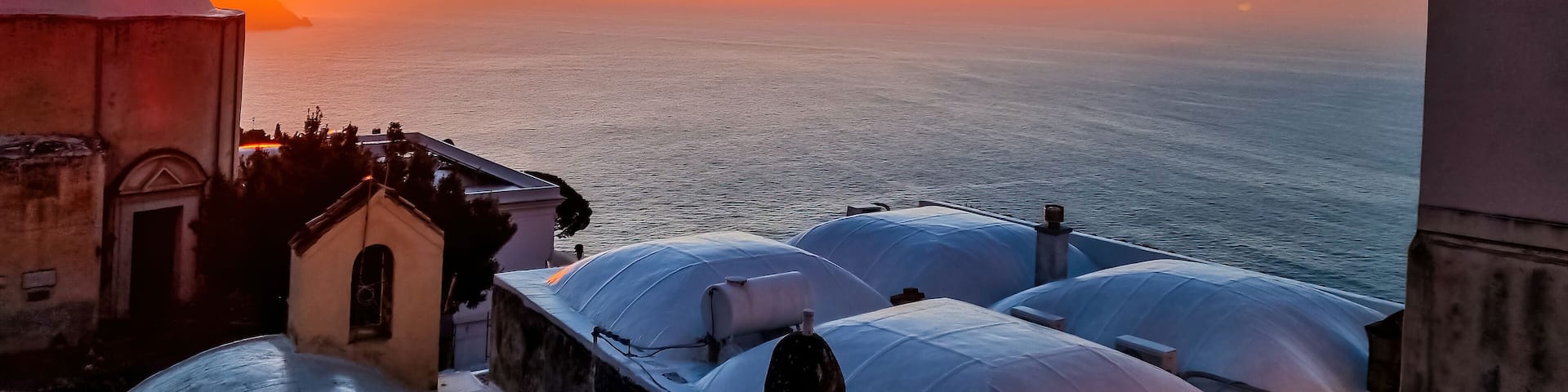 Panoramic view on church Chiesa Nuova during sunrise. Golden hour in coastal town Positano, Amalfi Coast, Italy, Campania, Europe. Vacation at coastline at the Mediterranean Sea. Praiano in distance