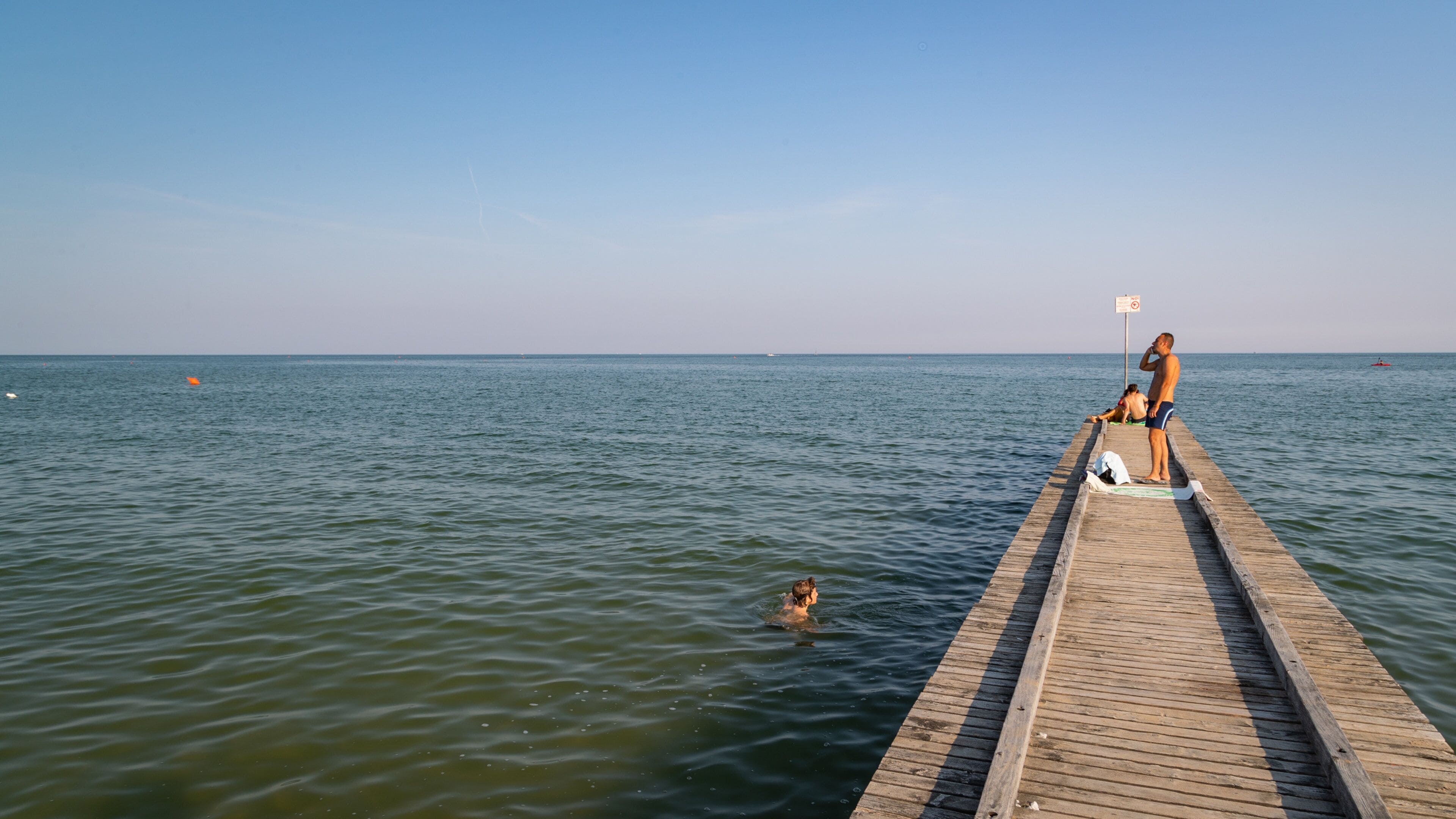 A wooden pier extending into calm waters with a clear sky.