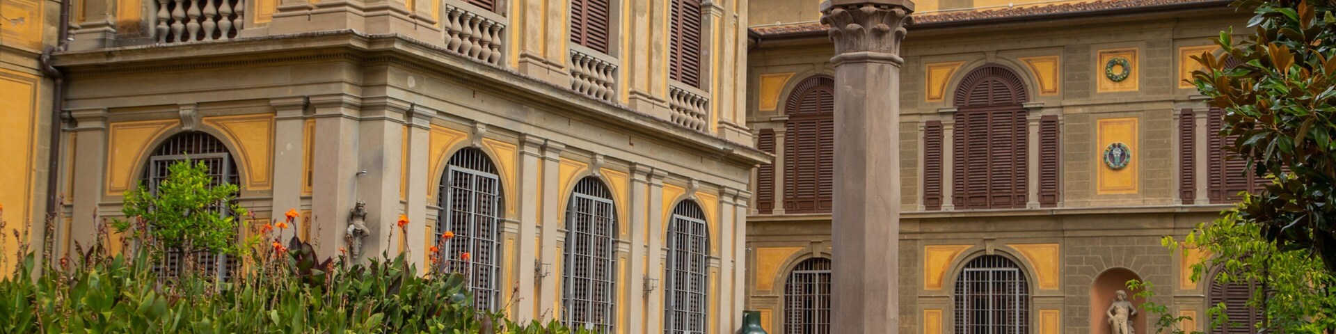 Un edificio histórico con ventanas de arco y una estatua sobre un pedestal.