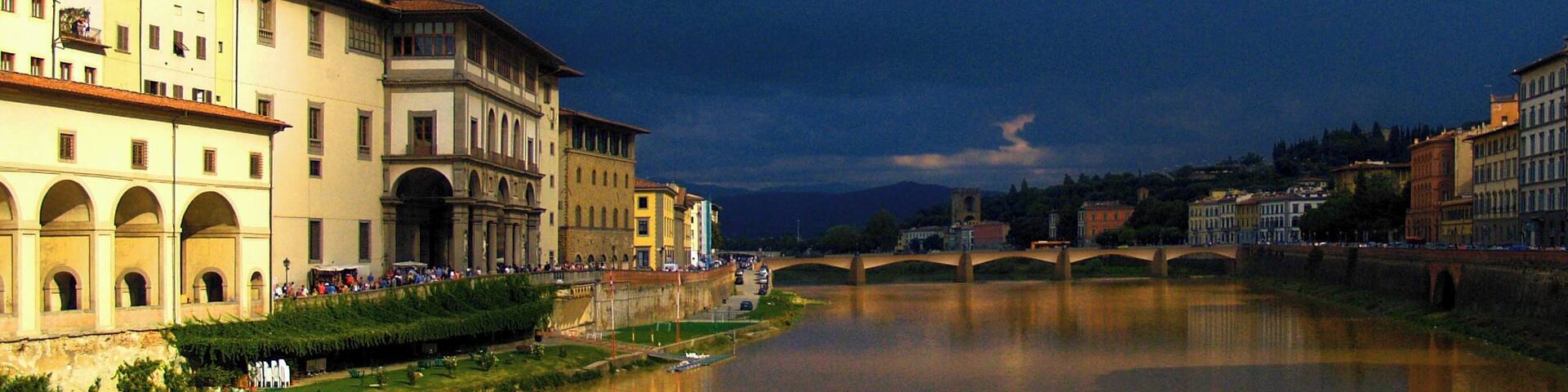A river with a bridge, buildings, and a crowd of people.