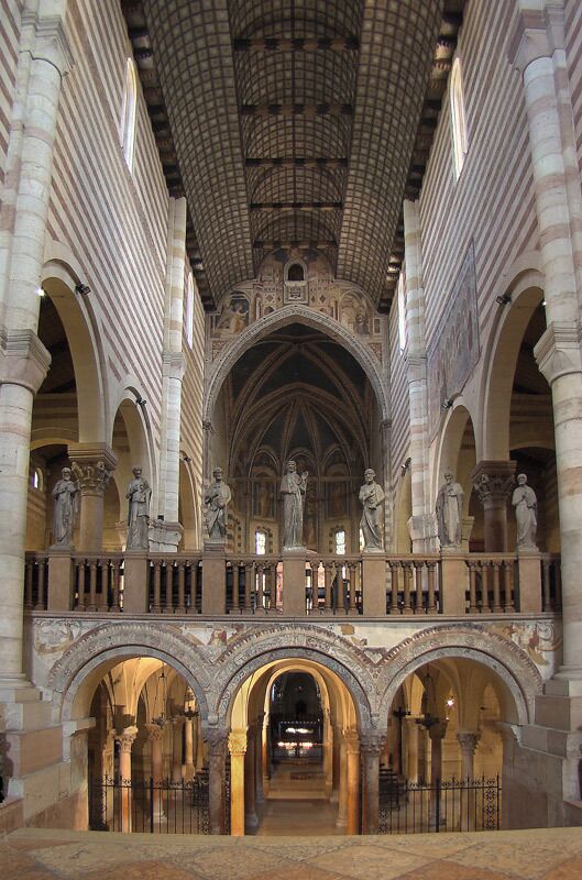 An interior of a cathedral with arched ceilings, statues, and a central aisle.