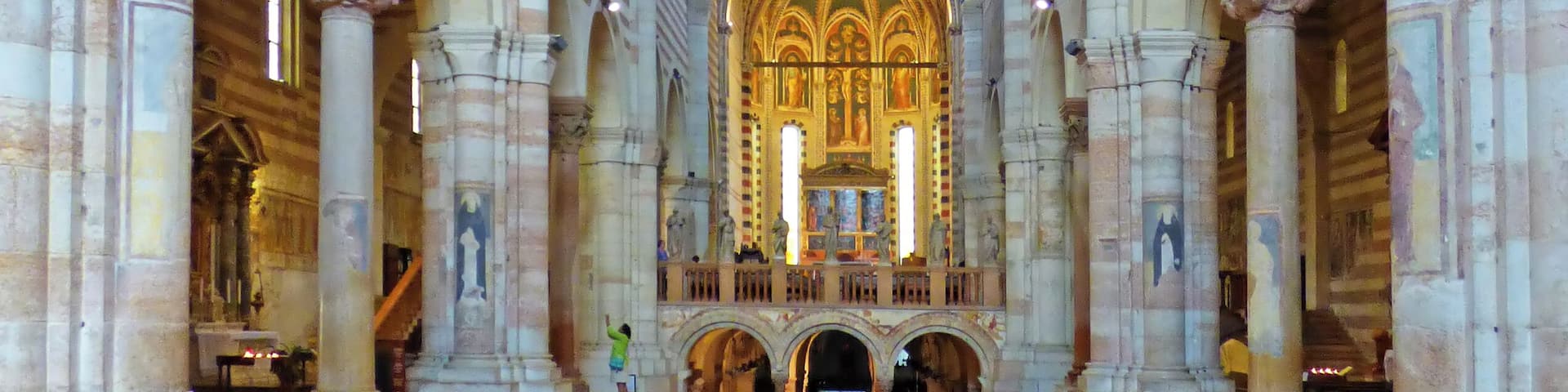 A cathedral interior with a checkered floor, arched columns, and a patterned ceiling.
