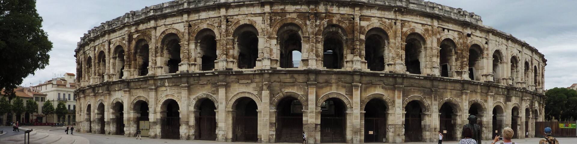 An ancient amphitheater with multiple arches and a large open space in front.