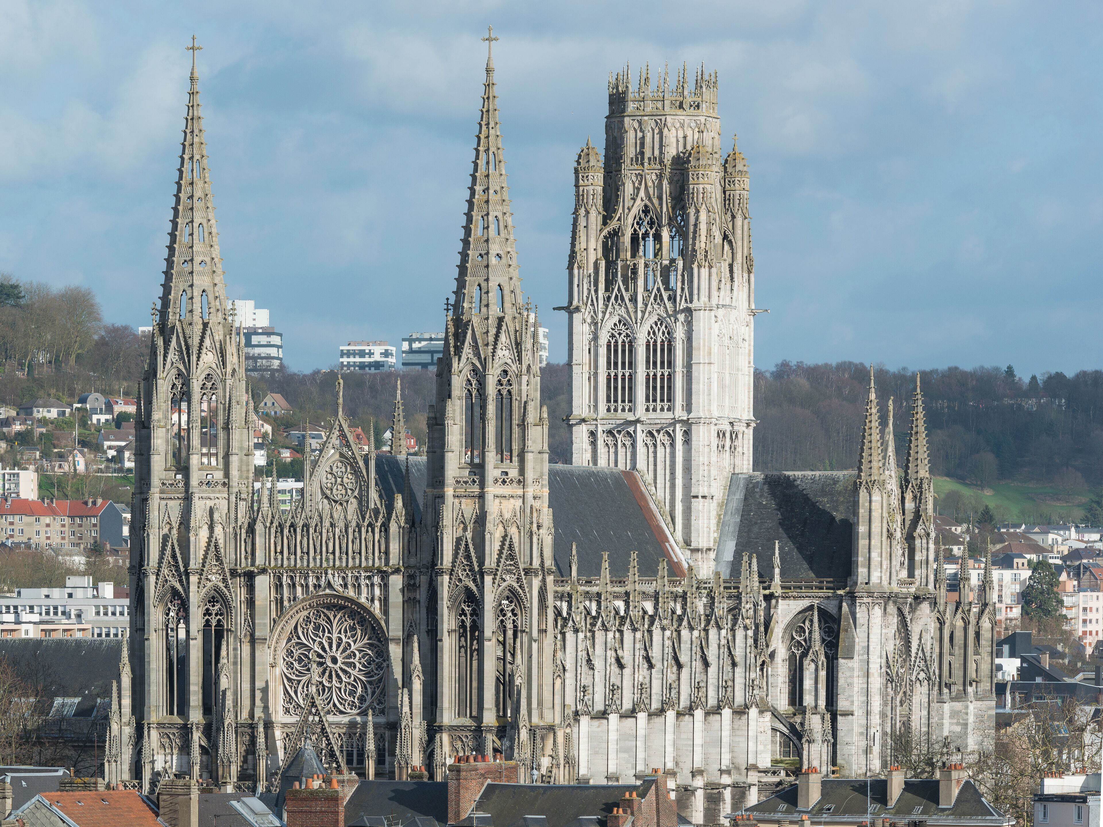 Uma catedral gótica com torres elaboradas e um grande vitral de rosa.