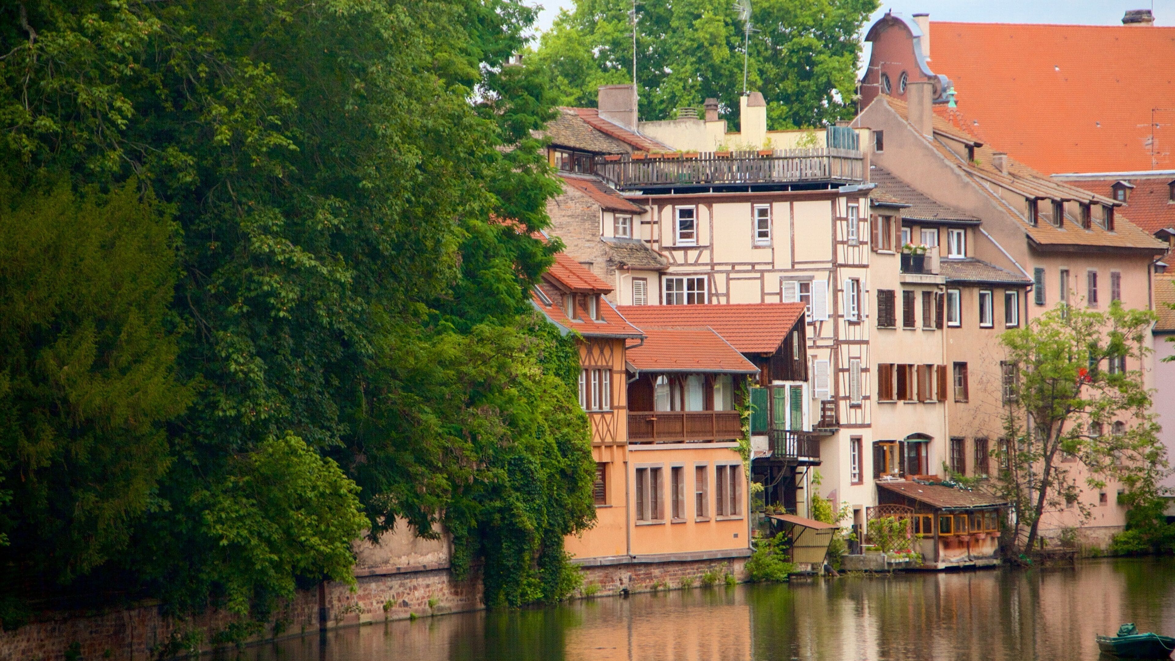 A riverside town with historic buildings, a bridge, and lush greenery.