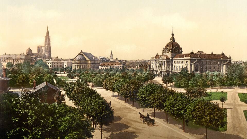 A historical cityscape with prominent buildings, including a large palace with a dome, a cathedral, and a church with a tall spire.