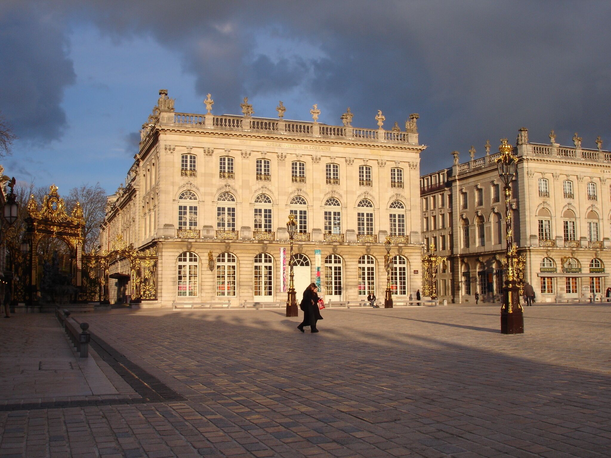 Un edificio histórico con arquitectura ornamentada y una plaza pavimentada frente a él.