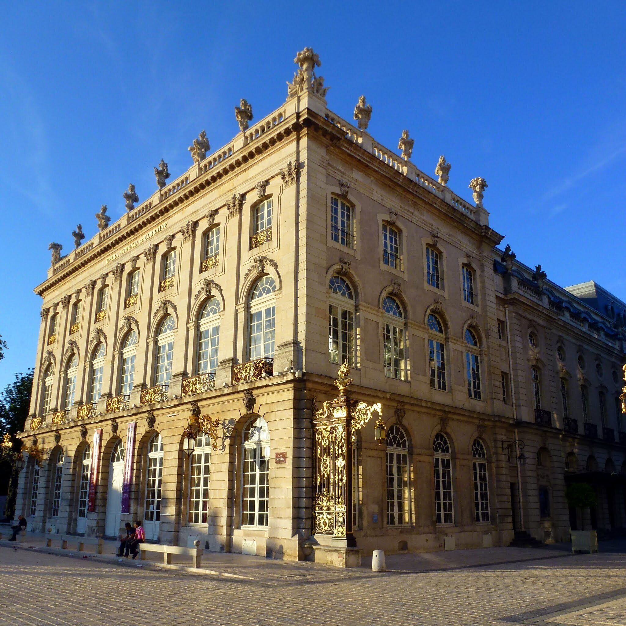 Un edificio histórico con arquitectura ornamentada, que presenta columnas, estatuas y una amplia entrada en arco.
