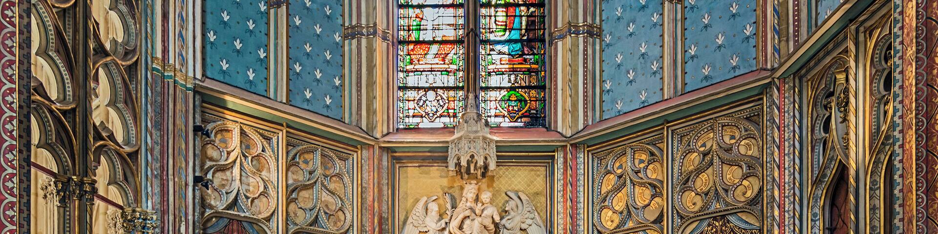 A richly decorated altar with intricate carvings and a stained glass window above.