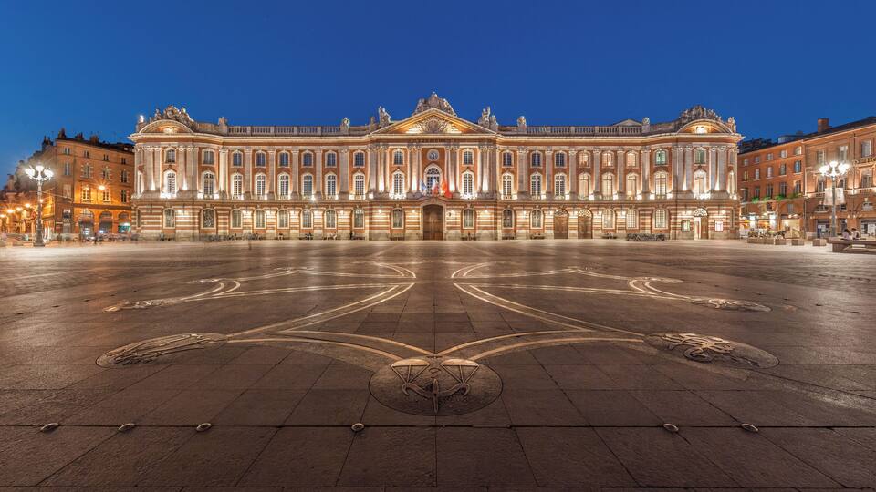 A grand, illuminated building with a symmetrical facade and a central courtyard.