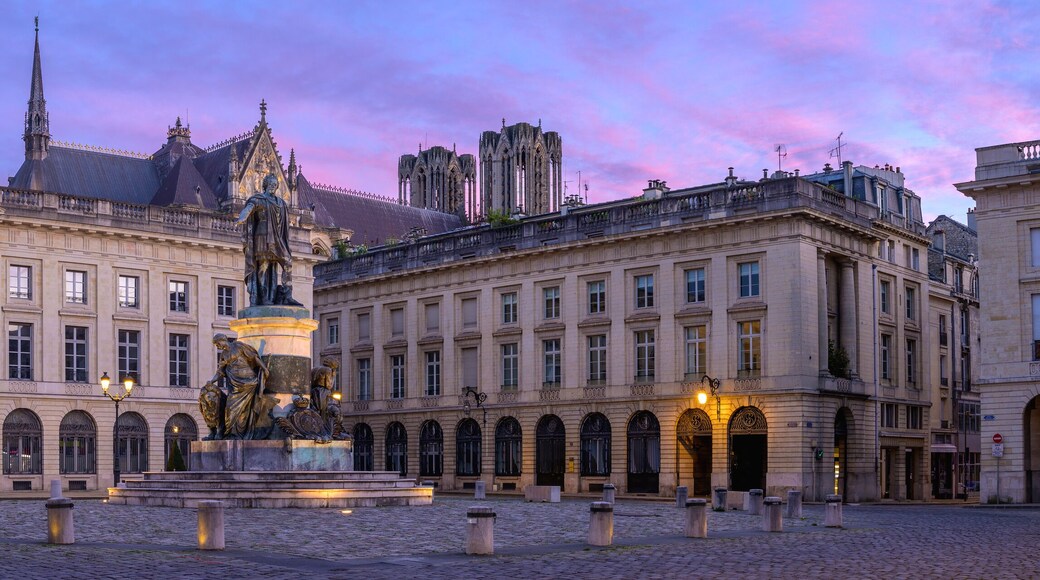 Ein historischer Platz mit einer Statue, klassischer Architektur und einem markanten Turm.