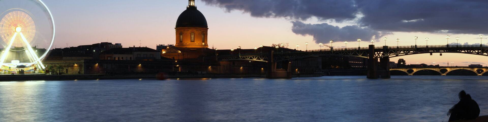 A river with a bridge and a large dome-like building.