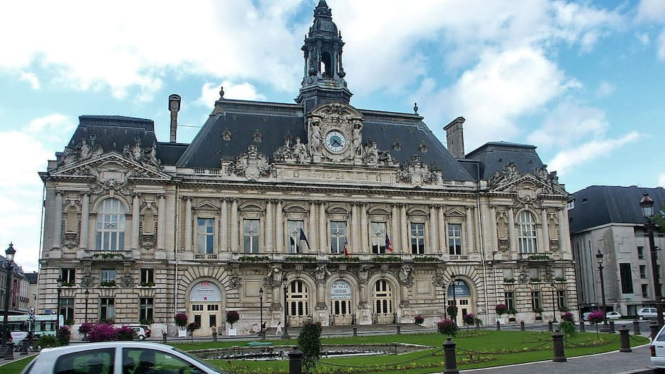 A historic building with a clock tower, ornate facade, and flags.