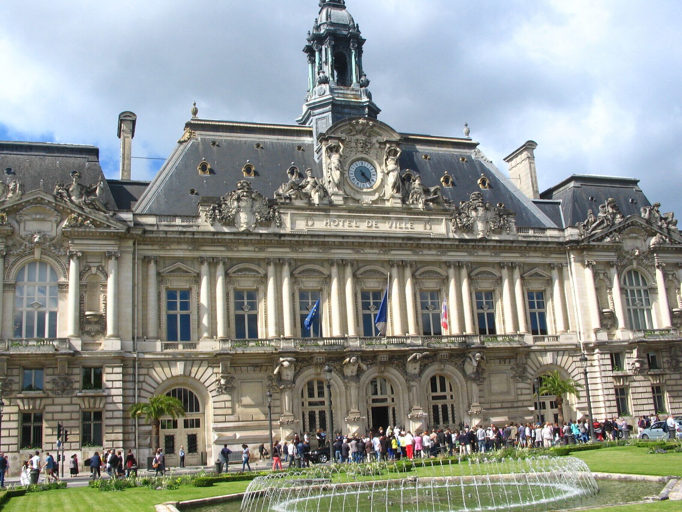 El Hotel de Ville de París, con una arquitectura ornamentada y una gran multitud en su fachada.
