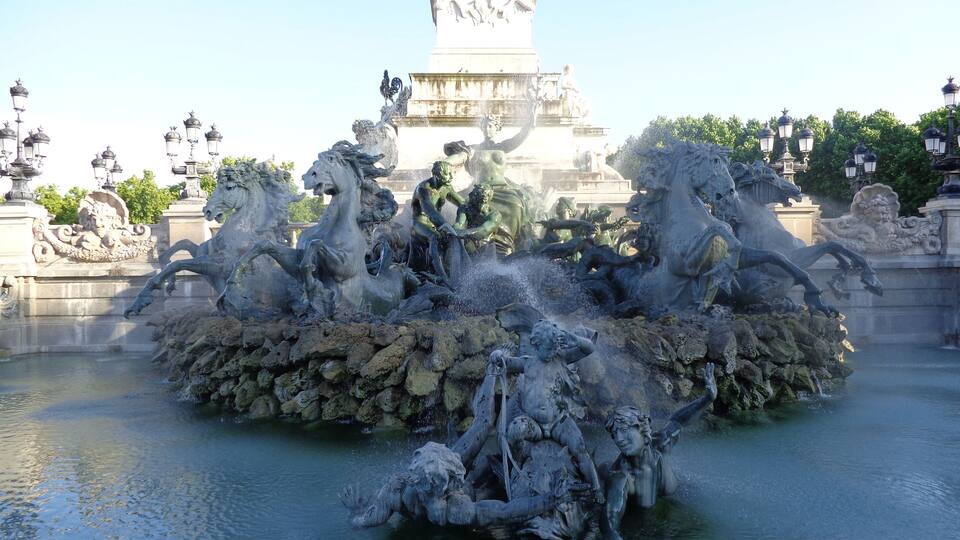 A large, ornate fountain with multiple statues of horses and riders, surrounded by water.
