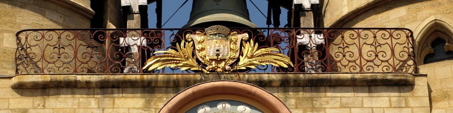 A large clock with Roman numerals and ornate gold detailing on a stone building.