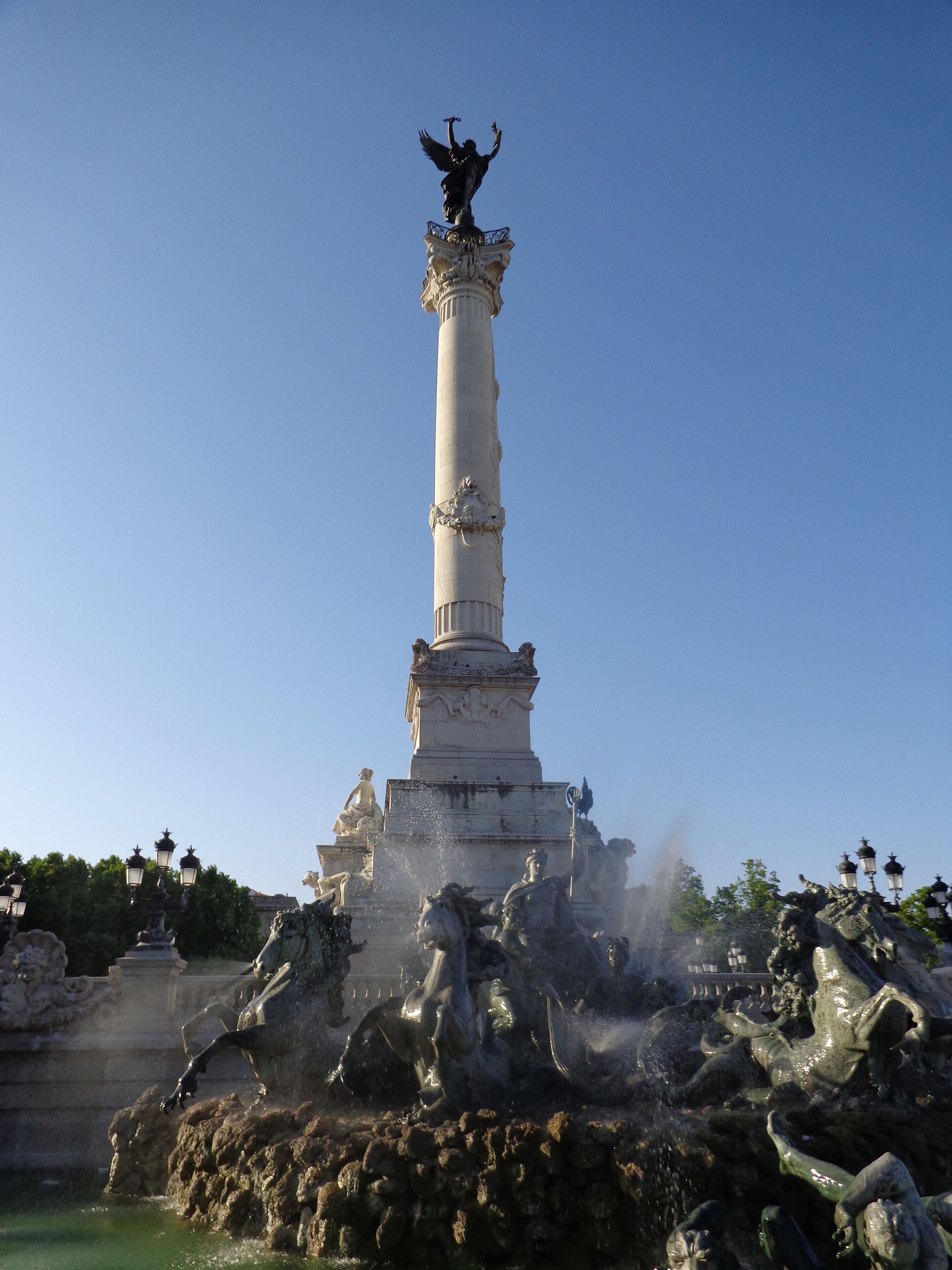 A tall column with a statue on top and a fountain at the base.