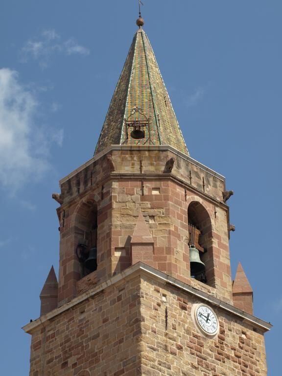 A clock tower with a pointed roof and a bell.