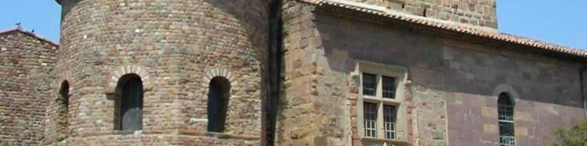 A historic stone church with a bell tower and a round tower.