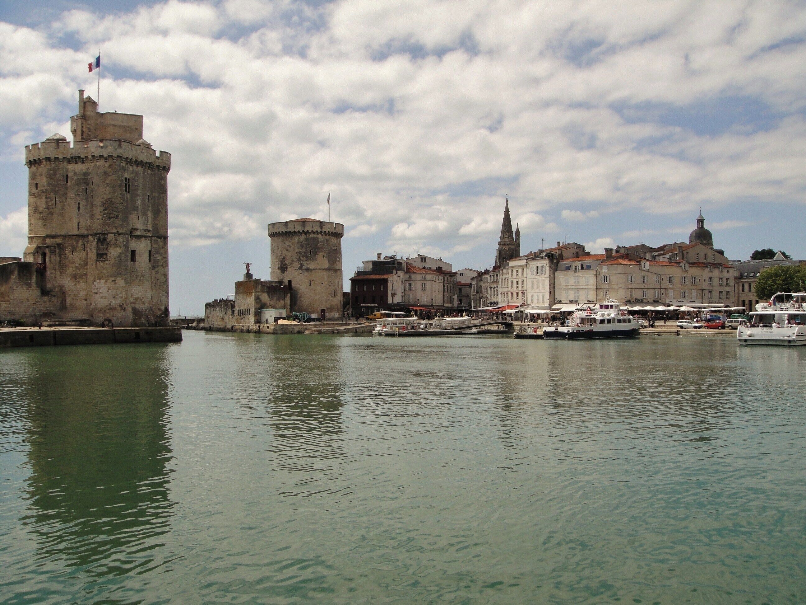 A historic waterfront with a prominent tower, a church spire, and a mix of old and new buildings.