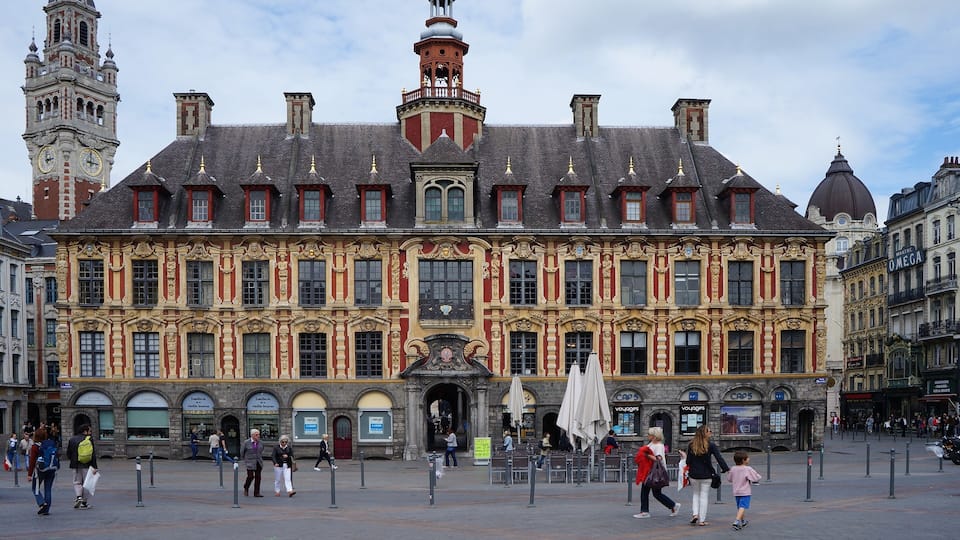 Un bâtiment historique à l’architecture riche et ornée, doté d’une tour horloge et d’une entrée centrale.
