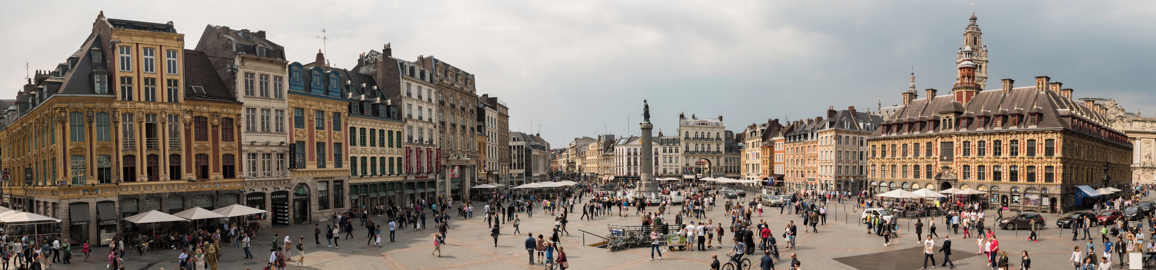 Een levendig plein met historische gebouwen, een standbeeld en voetgangers.