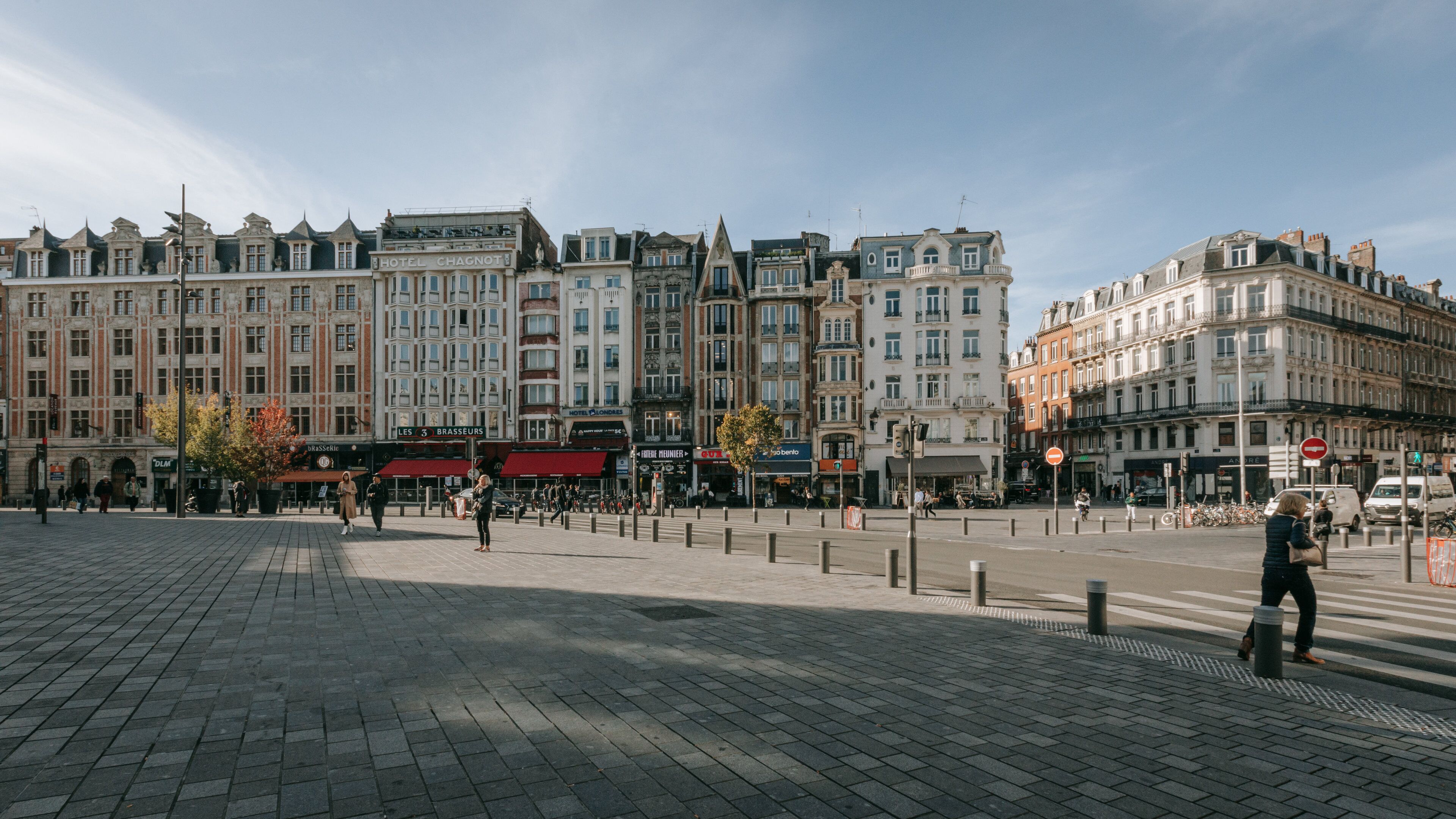 Ein historischer europäischer Stadtplatz mit Kopfsteinpflaster, klassischer Architektur und verschiedenen Geschäften sowie Cafés.