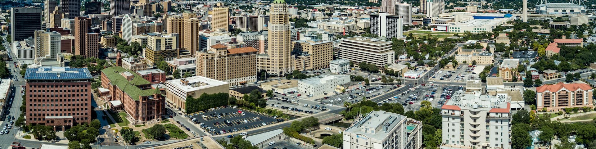 A cityscape with a variety of buildings, including a prominent tower, under a partly cloudy sky.