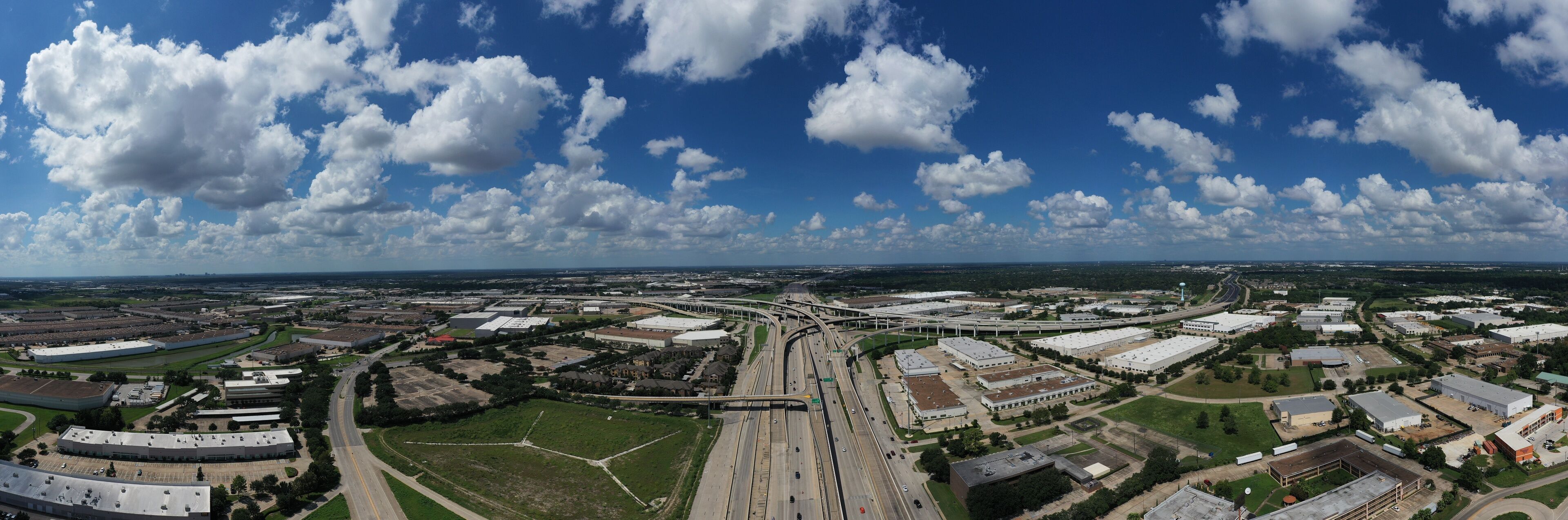 An aerial view of a large industrial area with multiple buildings, roads, and a highway interchange.